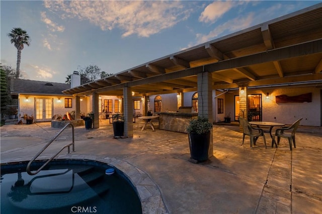 patio terrace at dusk featuring french doors and a bar