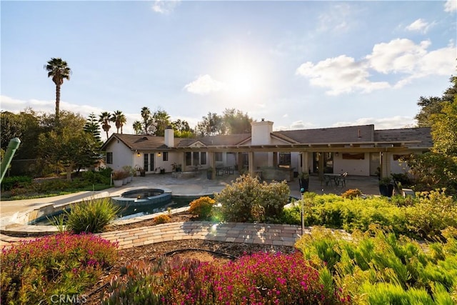 rear view of house featuring a pool with hot tub and a patio