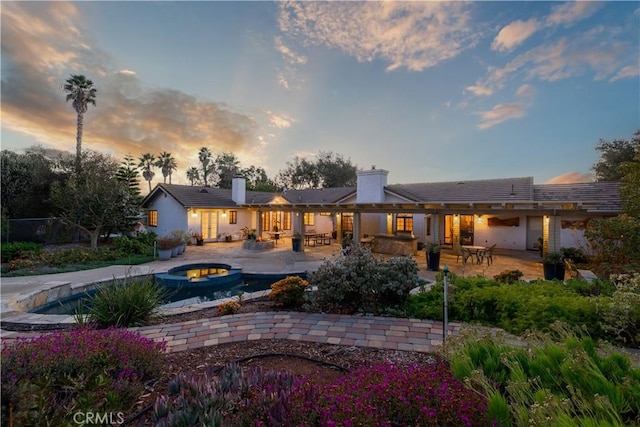 back house at dusk featuring a patio area