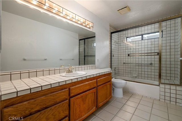 full bathroom with vanity, tile patterned floors, toilet, and combined bath / shower with glass door