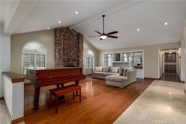 living room with hardwood / wood-style floors, high vaulted ceiling, a fireplace, beamed ceiling, and ceiling fan