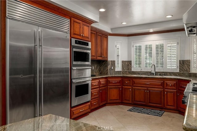 kitchen with stainless steel appliances, stone countertops, sink, and decorative backsplash