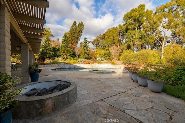 view of patio with a swimming pool with hot tub and an outdoor fire pit