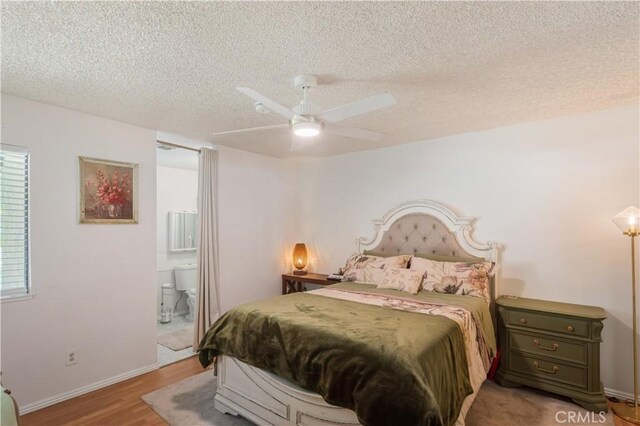 bedroom featuring a textured ceiling, light wood finished floors, connected bathroom, and a ceiling fan