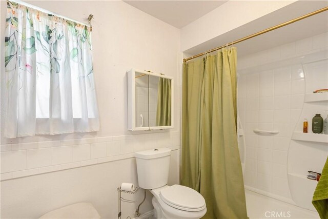 bathroom featuring shower / bath combination with curtain and toilet