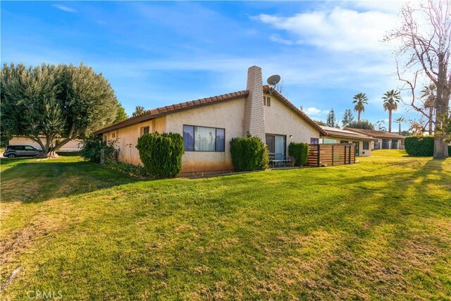 view of property exterior with a lawn, fence, and stucco siding