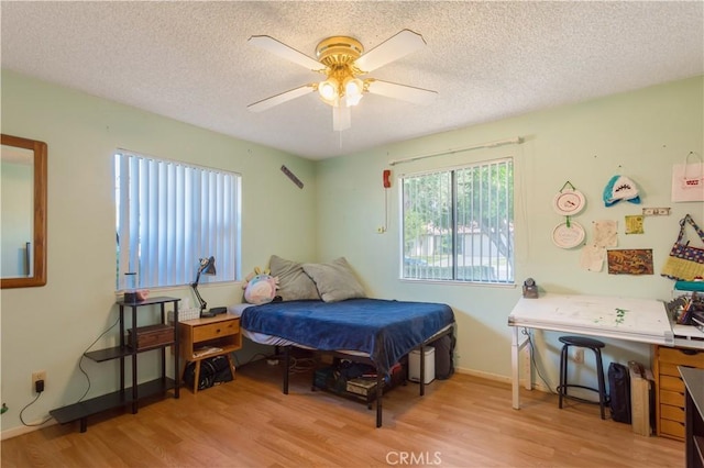 bedroom with ceiling fan, a textured ceiling, and wood finished floors