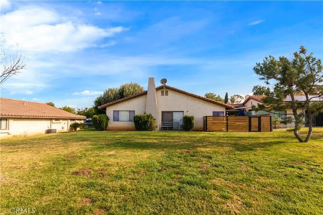 view of home's exterior featuring a lawn, fence, and stucco siding