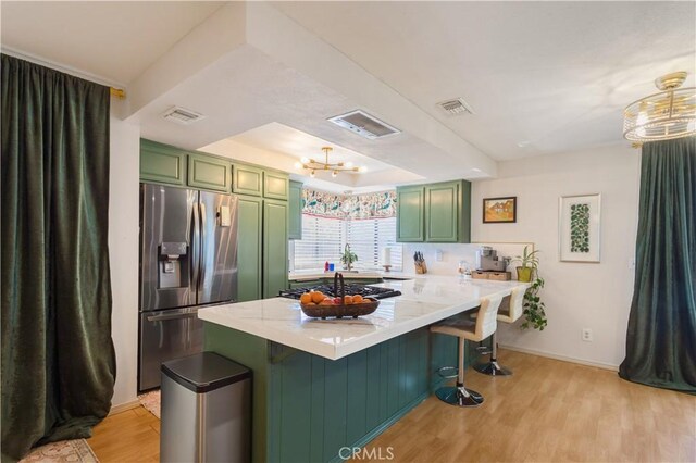 kitchen with a raised ceiling, stainless steel fridge with ice dispenser, a peninsula, light wood-type flooring, and green cabinets