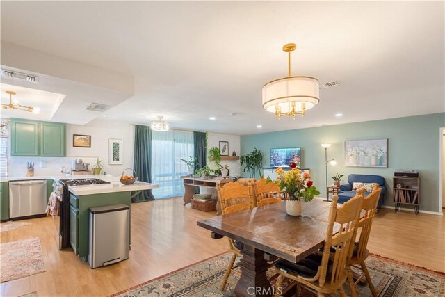 dining area with a chandelier, light wood-type flooring, and visible vents