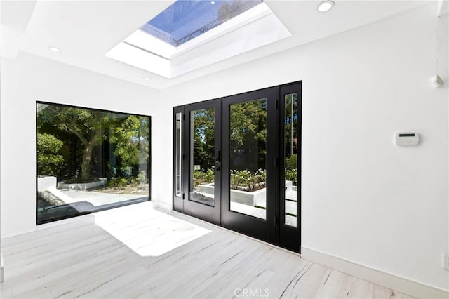 doorway with a skylight, plenty of natural light, and french doors