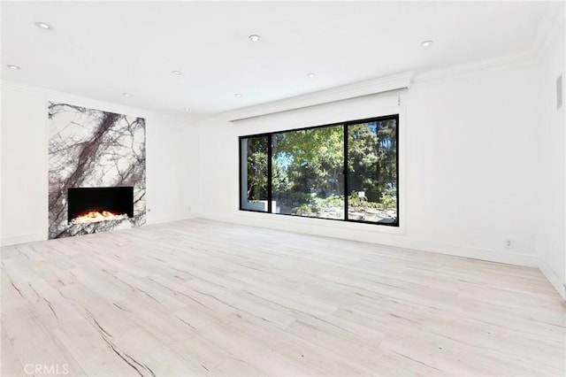 unfurnished living room featuring crown molding, a fireplace, and light hardwood / wood-style flooring