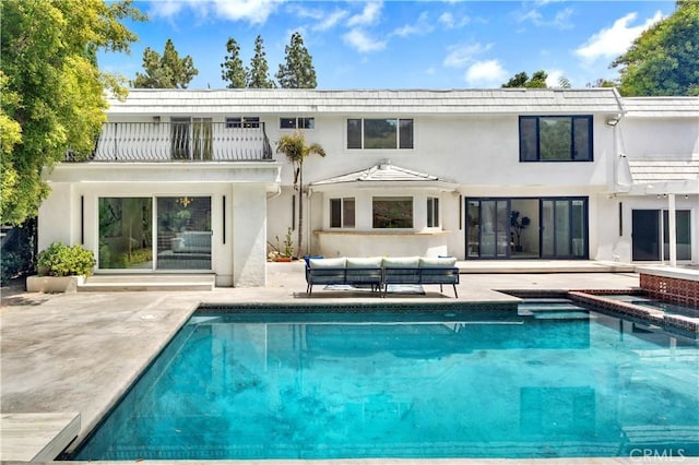 rear view of property with a balcony, outdoor lounge area, and a patio area