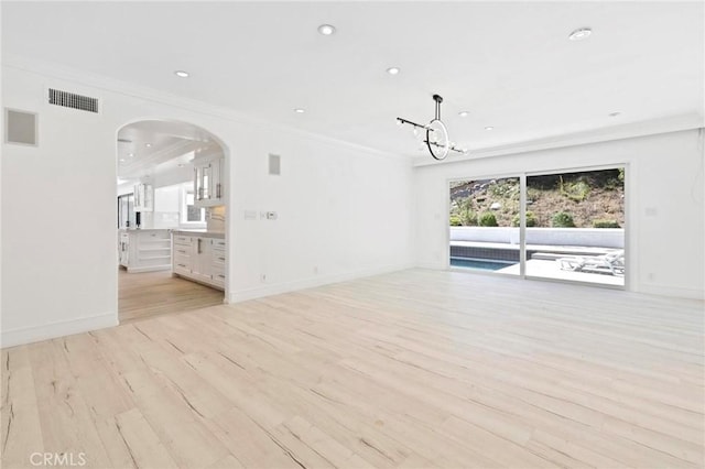 unfurnished living room featuring crown molding, a chandelier, and light hardwood / wood-style flooring