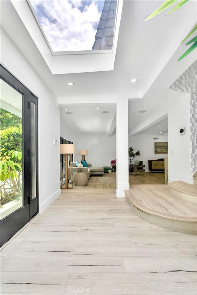 foyer with light hardwood / wood-style floors and a skylight