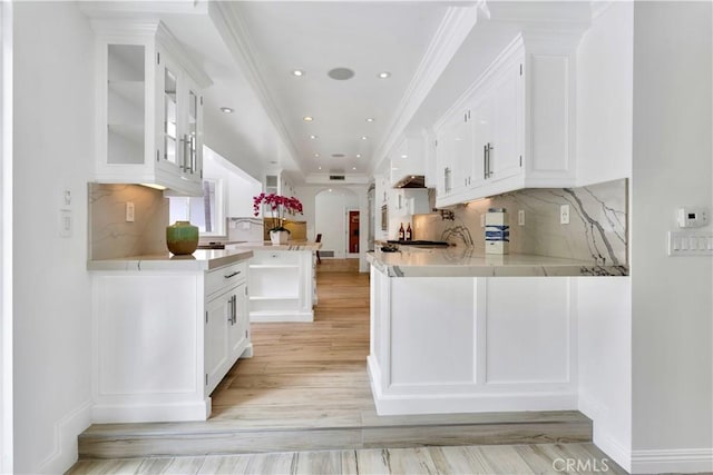 kitchen with tasteful backsplash, kitchen peninsula, light hardwood / wood-style floors, and white cabinets