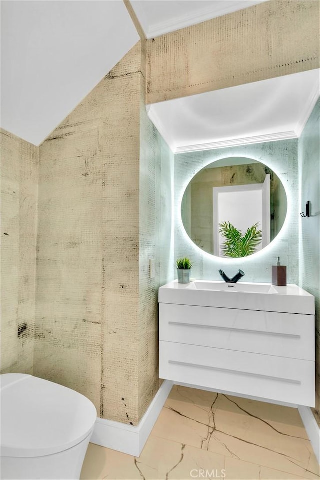 bathroom with vanity, vaulted ceiling, ornamental molding, and toilet