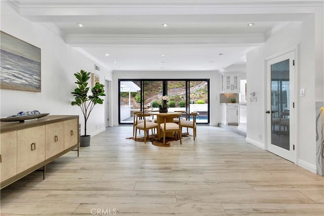 dining space with beamed ceiling, ornamental molding, and light wood-type flooring