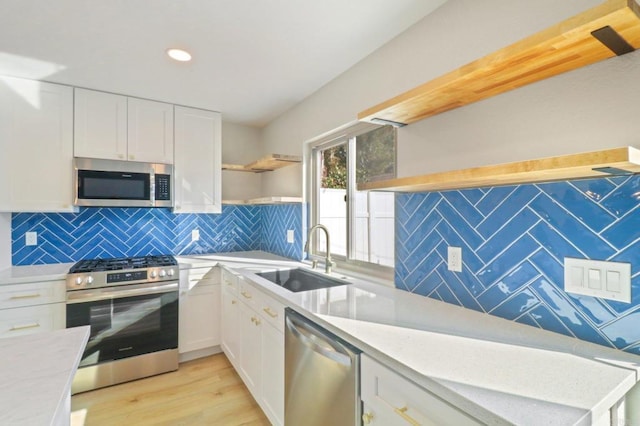 kitchen with sink, appliances with stainless steel finishes, white cabinetry, tasteful backsplash, and light wood-type flooring