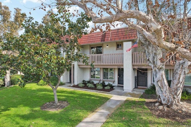 view of front of home featuring a front lawn and a balcony