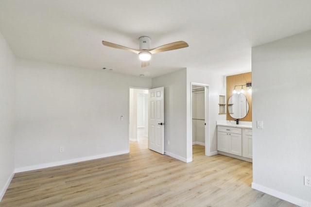 unfurnished bedroom with ceiling fan, a spacious closet, a closet, and light wood-type flooring