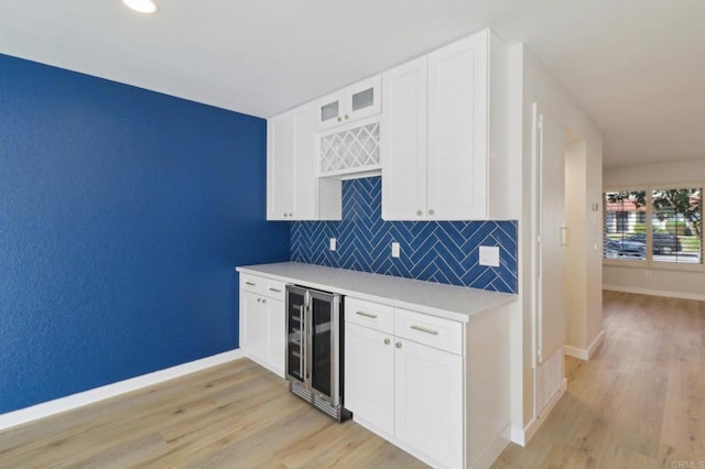 kitchen featuring white cabinetry, tasteful backsplash, beverage cooler, and light hardwood / wood-style flooring