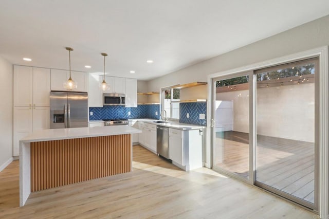 kitchen featuring stainless steel appliances, hanging light fixtures, a kitchen island, and white cabinets