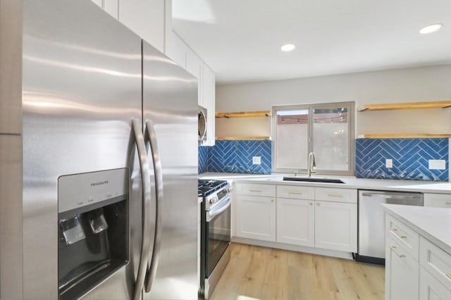 kitchen with sink, light hardwood / wood-style flooring, stainless steel appliances, decorative backsplash, and white cabinets