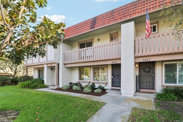 view of front of house featuring a front lawn and a balcony