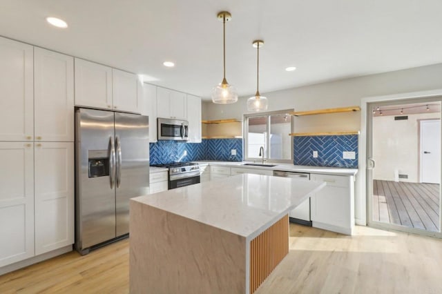 kitchen with stainless steel appliances, white cabinetry, a kitchen island, and pendant lighting