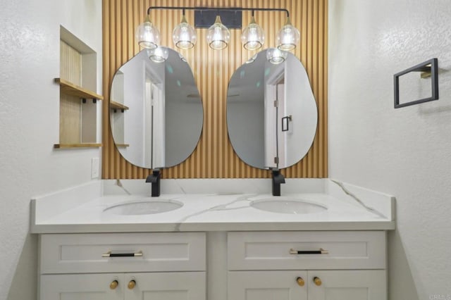 full bath with a sink, double vanity, and a textured wall