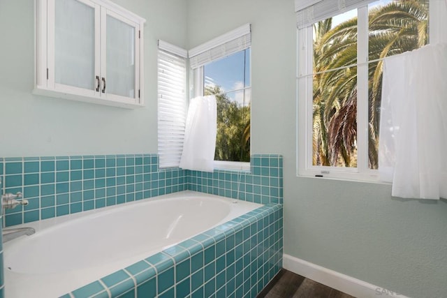 bathroom with hardwood / wood-style flooring and tiled bath