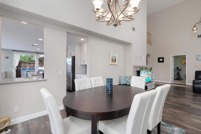 dining area with a fireplace, dark hardwood / wood-style flooring, and a towering ceiling