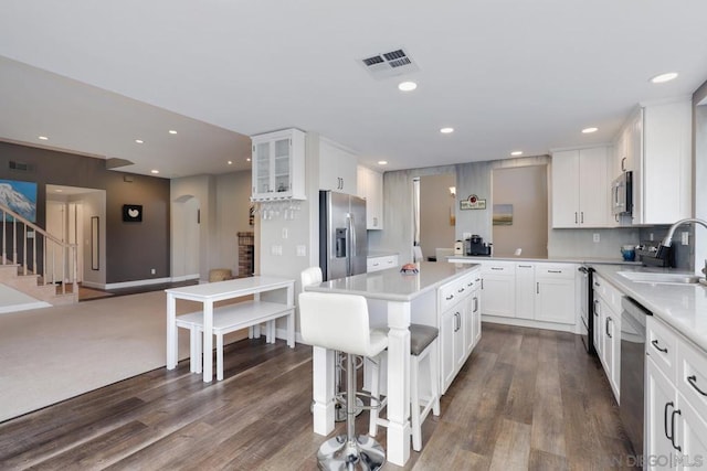 kitchen featuring sink, stainless steel appliances, a kitchen breakfast bar, white cabinets, and a kitchen island