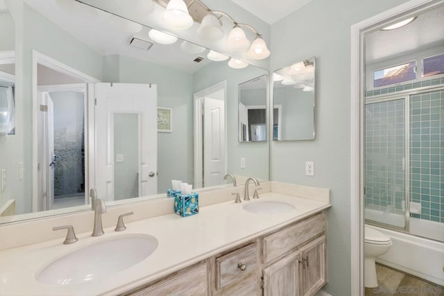 full bathroom featuring hardwood / wood-style flooring, enclosed tub / shower combo, vanity, and toilet