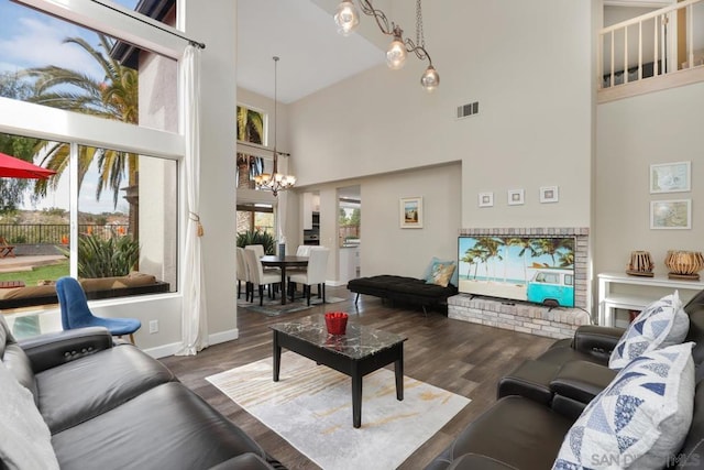 living room featuring a towering ceiling, an inviting chandelier, and dark hardwood / wood-style flooring