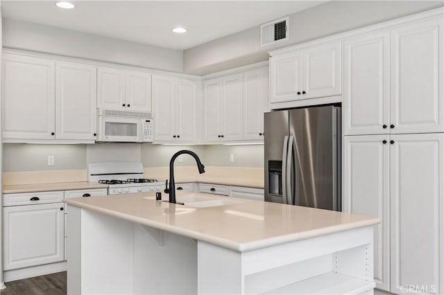 kitchen featuring sink, white cabinets, a kitchen island with sink, dark wood-type flooring, and white appliances