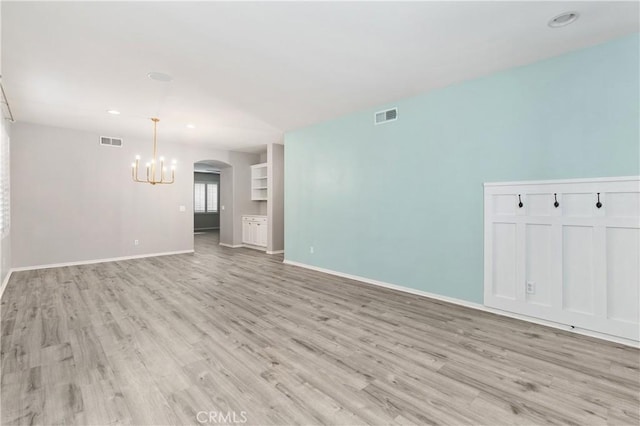 unfurnished room with an inviting chandelier and light wood-type flooring