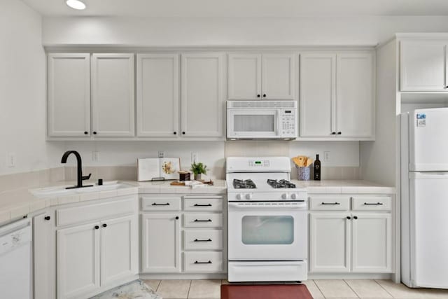 kitchen featuring white appliances, tile counters, and white cabinets