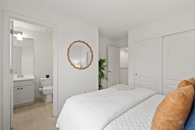 tiled bedroom with sink, ensuite bath, and a closet