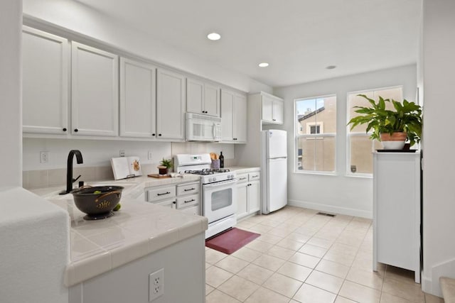 kitchen with light tile patterned flooring, sink, white cabinets, and white appliances