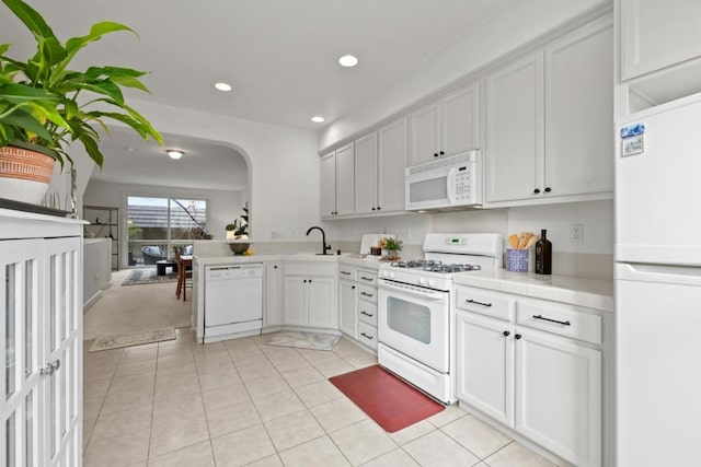 kitchen with sink, white appliances, light tile patterned floors, white cabinets, and tile countertops