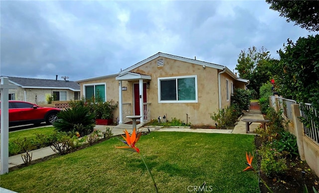 view of front of house featuring a front yard, fence, and stucco siding