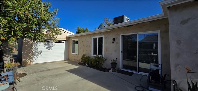 view of patio / terrace with concrete driveway, an attached garage, an outdoor structure, and central air condition unit