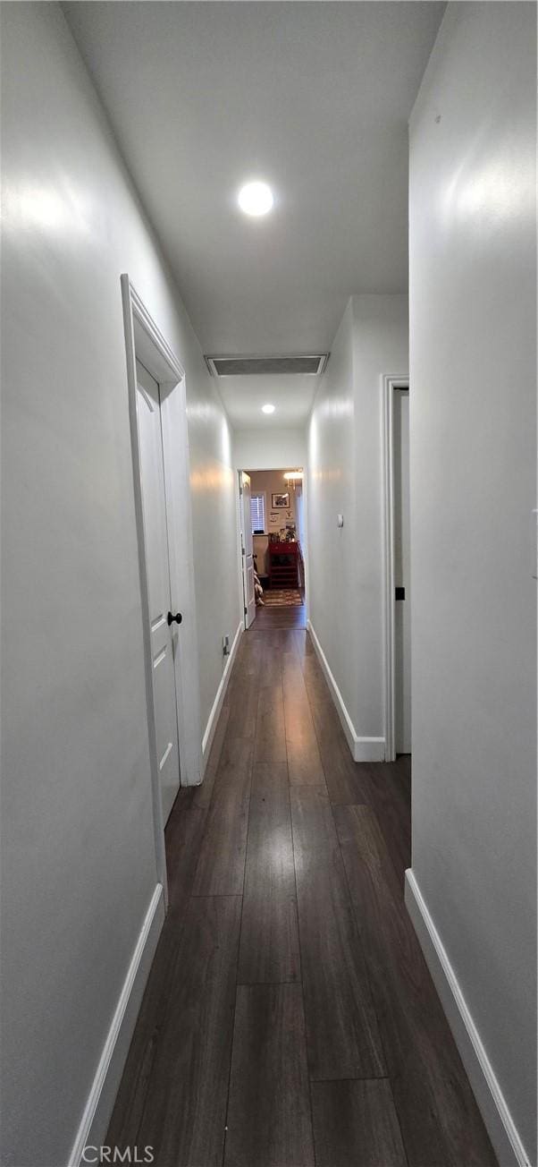 corridor featuring dark wood-style floors, visible vents, and baseboards