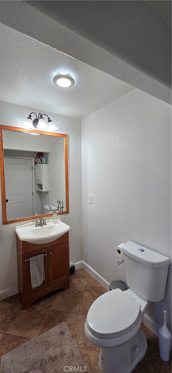 half bathroom with toilet, baseboards, a textured ceiling, and vanity