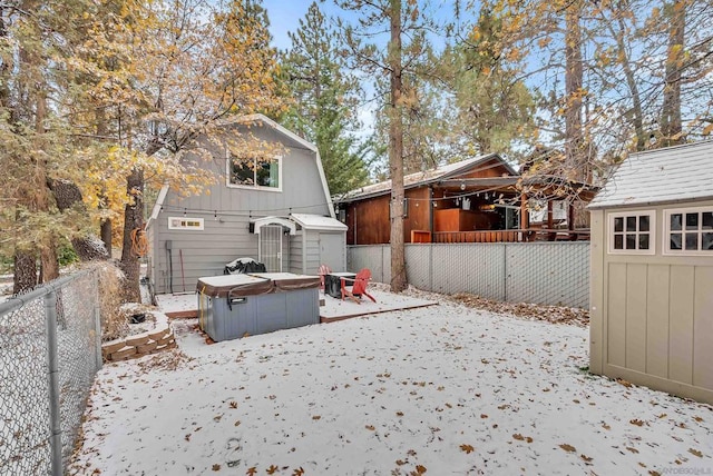 yard covered in snow with a hot tub and a storage unit