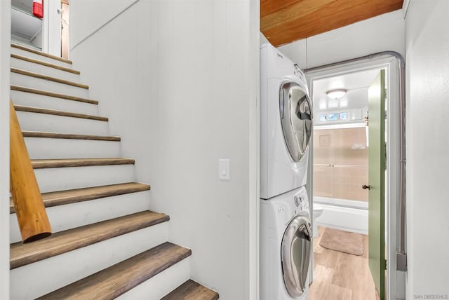 washroom with stacked washer and dryer and wood-type flooring