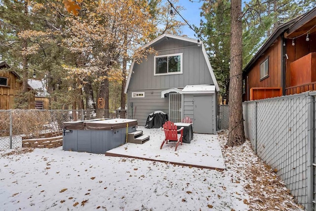 snow covered back of property featuring a hot tub