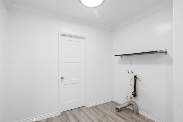 clothes washing area with crown molding and light hardwood / wood-style floors